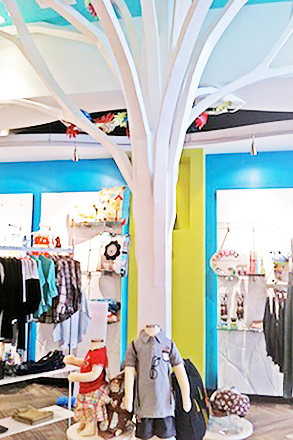 a tree camouflage structure painted in white that conceals the beam in the middle of the store