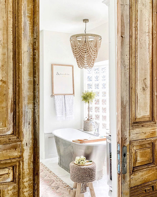 bathroom renovation in white with beaded chandelier, wall art, and antique wooden sliding doors at entry